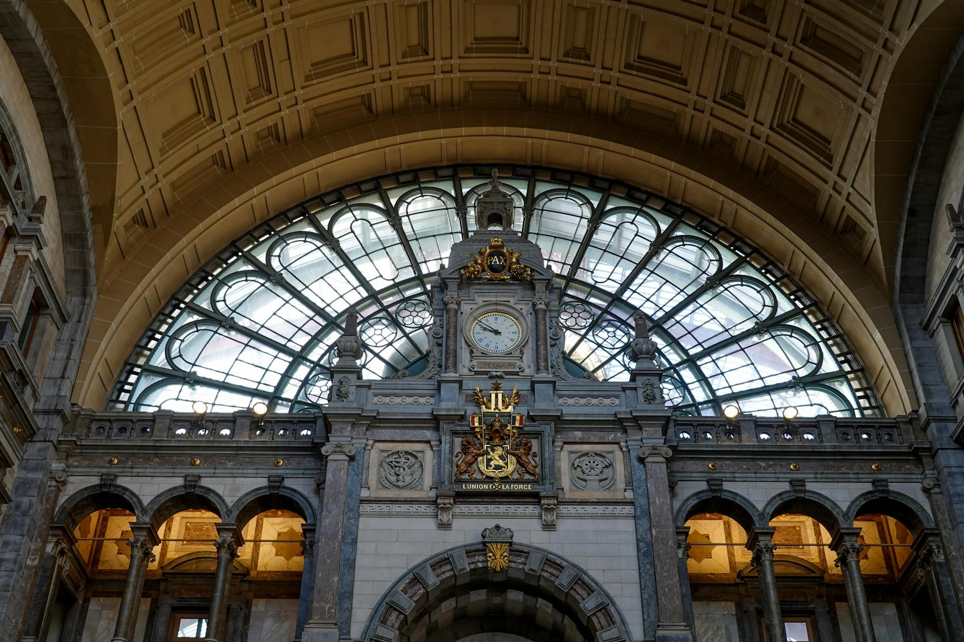 low angle shot of clock and coat of arms at antwerp central station belgium