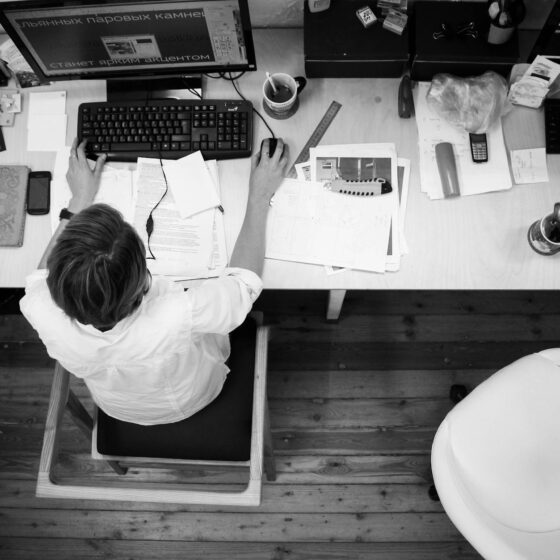 black and gray photo of person in front of computer monitor