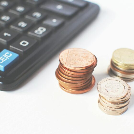 gold colored coins near calculator